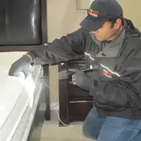 Bed bug inspection technician checking a mattress and bed frame for signs of infestation in Oakland, CA