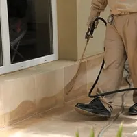General pest control technician spraying exterior perimeter around a home in Oakland, CA
