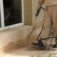 General pest control technician spraying exterior perimeter around a home in Oakland, CA