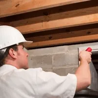 Termite inspection technician checking a basement wall and framing for termite activity in Oakland, CA