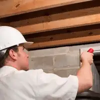 Termite inspection technician checking a basement wall and framing for termite activity in Oakland, CA